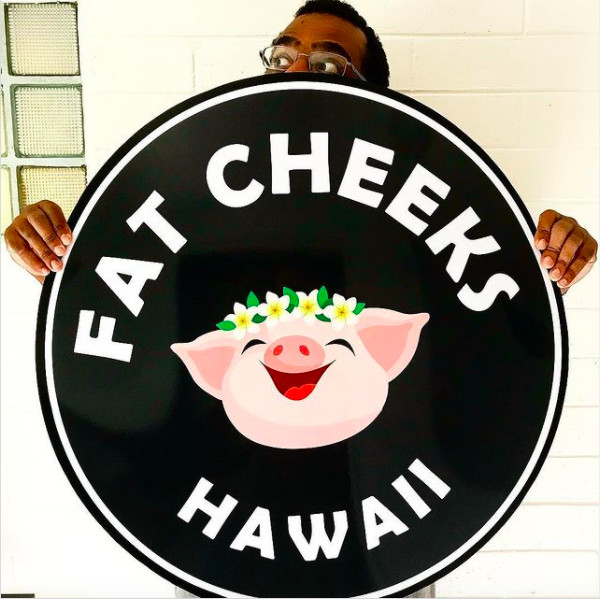Jared Brown, owner of Fat Cheeks, holds a sign up for Fat Cheeks restaurant