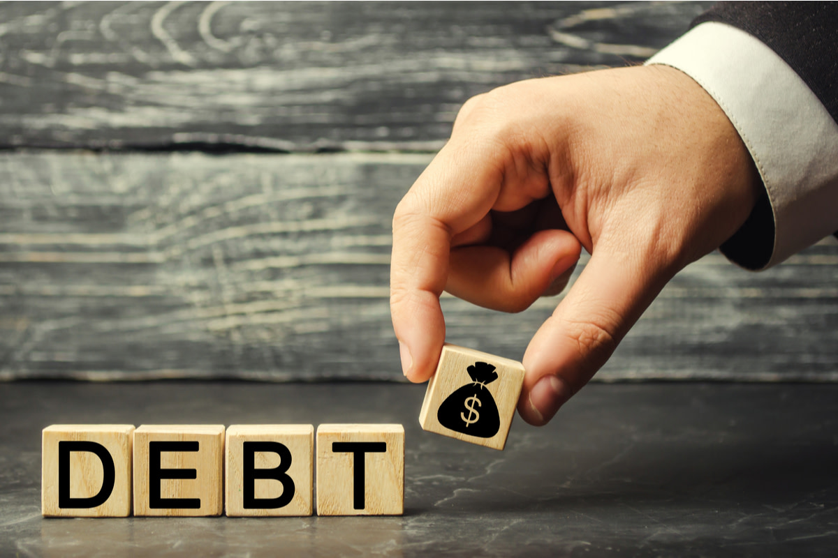 Wooden blocks with the word debt and the image of dollars