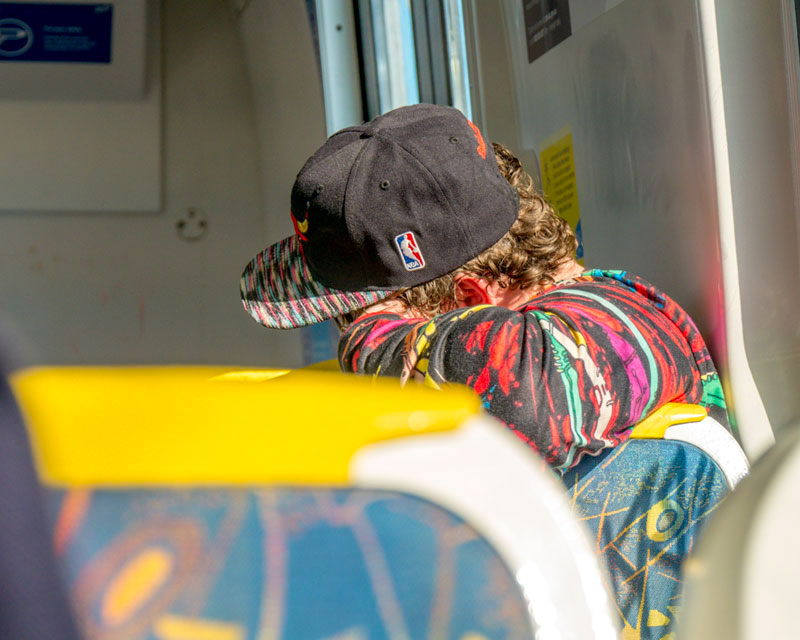 A photo of a young kid on the Melbourne Metro wearing a baseball cap