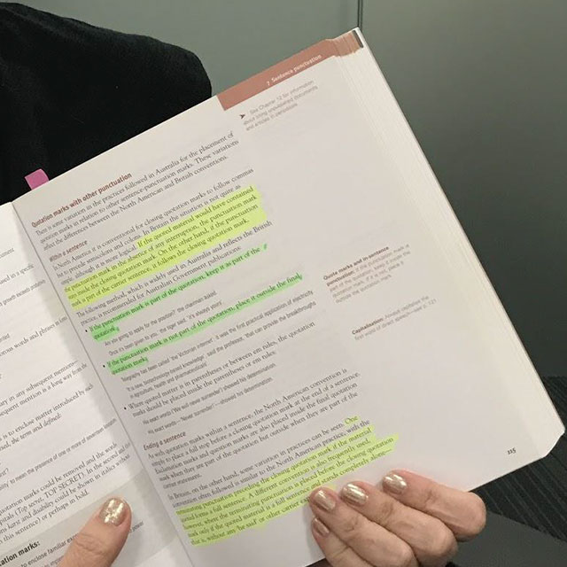 A copy of the Australian Style Manual being held open to show different highlighted sections, colours and notes that have been added on top.