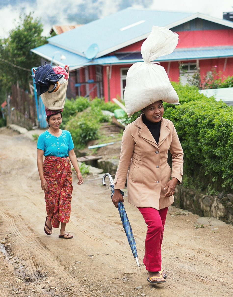 Two Myanmar women taking laundry up a hill on their heads