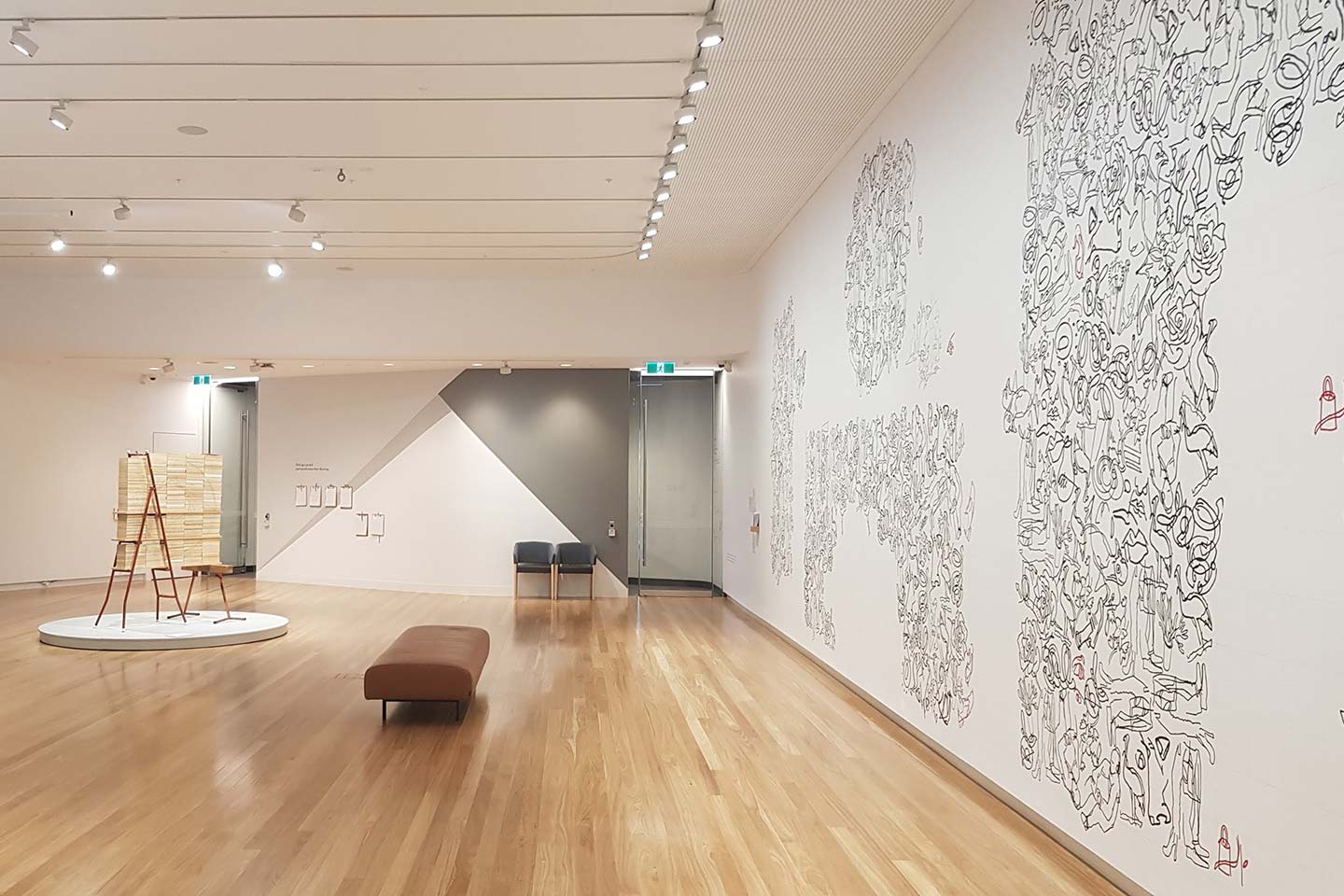 The exhibition space at Bunjil Place in City of Casey with an interactive puzzle drawn on the wall and a sculpture in the middle of the room.