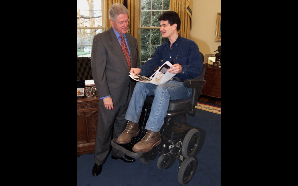 Dean Kamen, in IBOT—a powered wheelchair—, standing next to Bill Clinton in the Oval Office.
