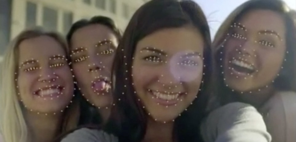Four women smiling while being analyzed by facial recognition software.