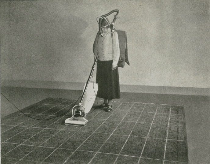 A woman uses a vacuum cleaner.