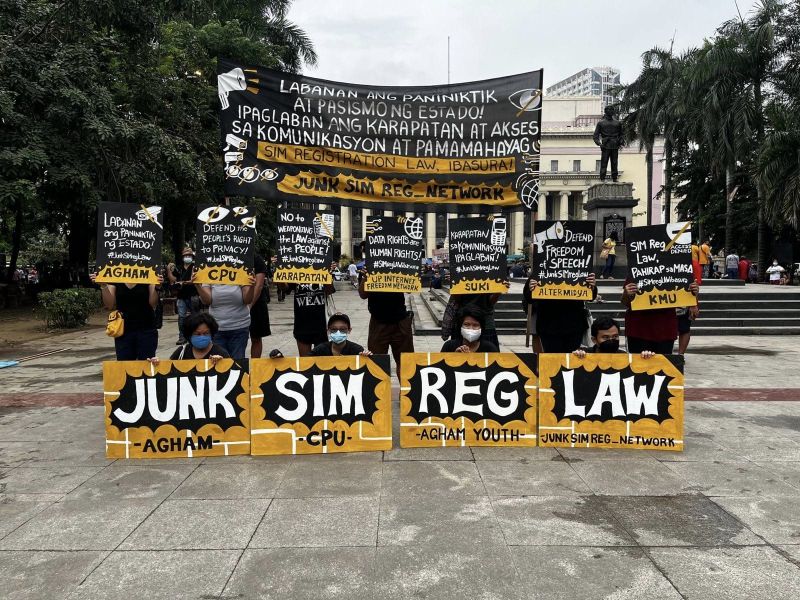 Photo of several masked Filipino anti-surveillance protesters with signage about the "Junk Sim Reg[istration] Law."  