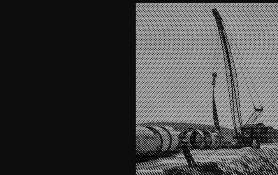 aliased black and white image of workers installing pipes underground with a crane