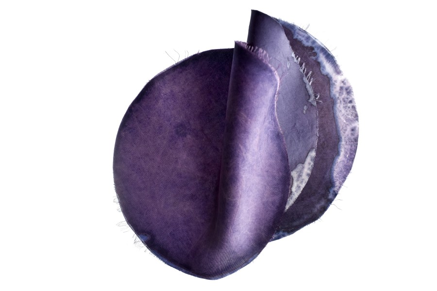 A piece of purple fabric, cut into a circle with raw ages.