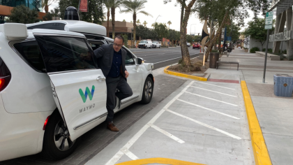 A Photo of Micah exiting a white, Waymo Pacifica minivan in Chandler