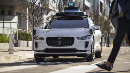  A photo of the Waymo Driver on a white I-PACE yielding to pedestrians in a crosswalk 