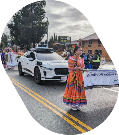 Waymo vehicle surrounded by participants of Kingdom Day Parade
