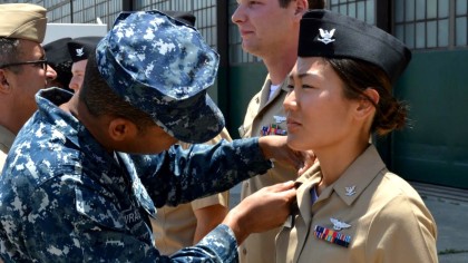 Lynn Kang in their Navy uniform receiving a pin.