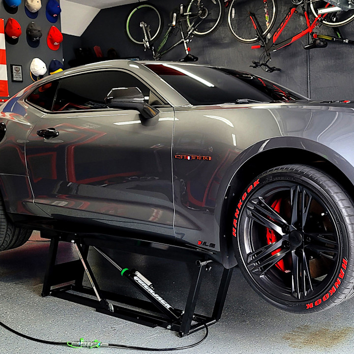 Gray Chevrolet Camaro raised on a QuickJack portable car lift in a home garage.