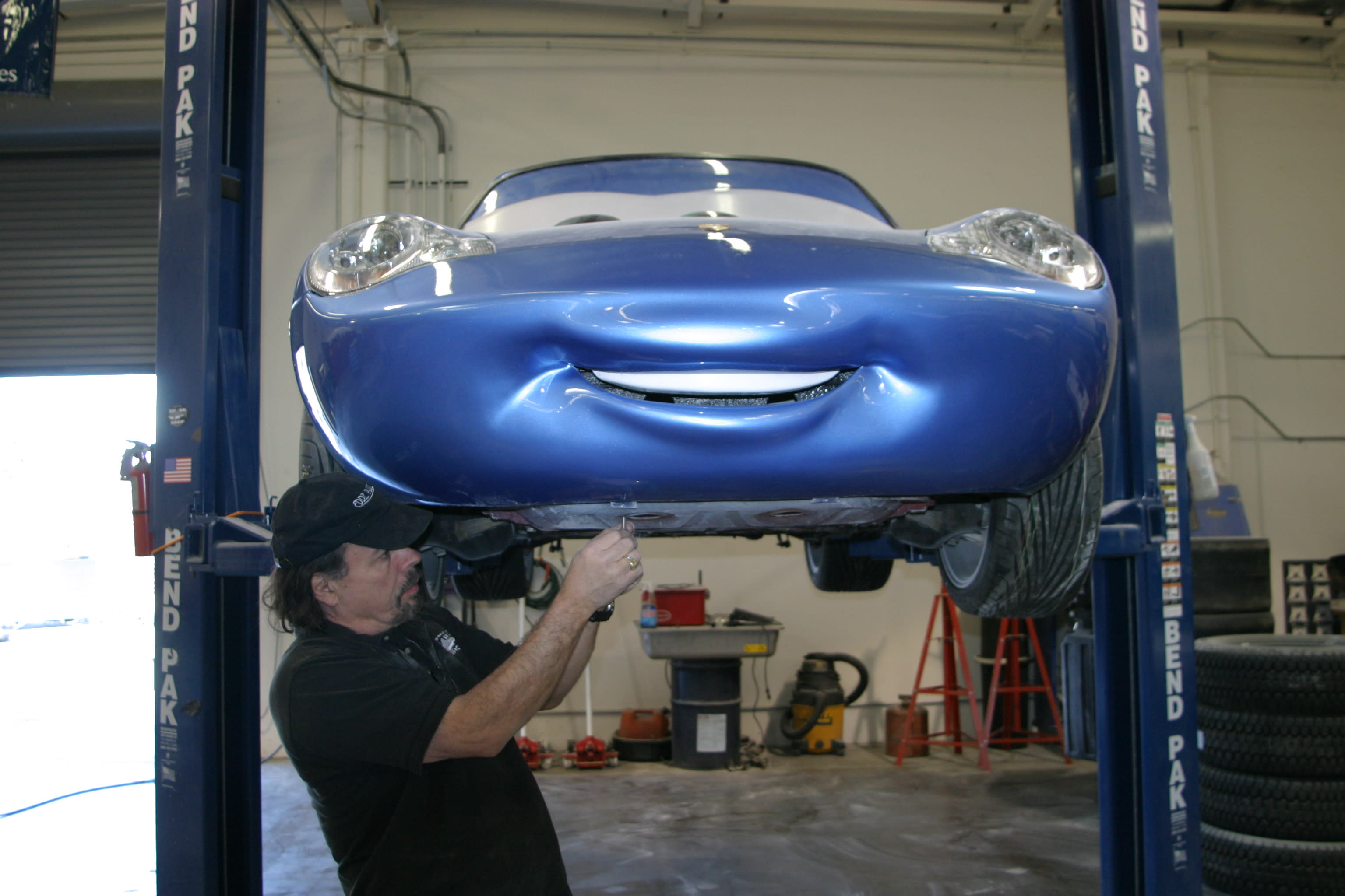 Mechanic Working Under Blue Sports Car on Lift