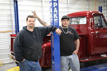 Mechanics In Garage With Classic Truck And BendPak Lift