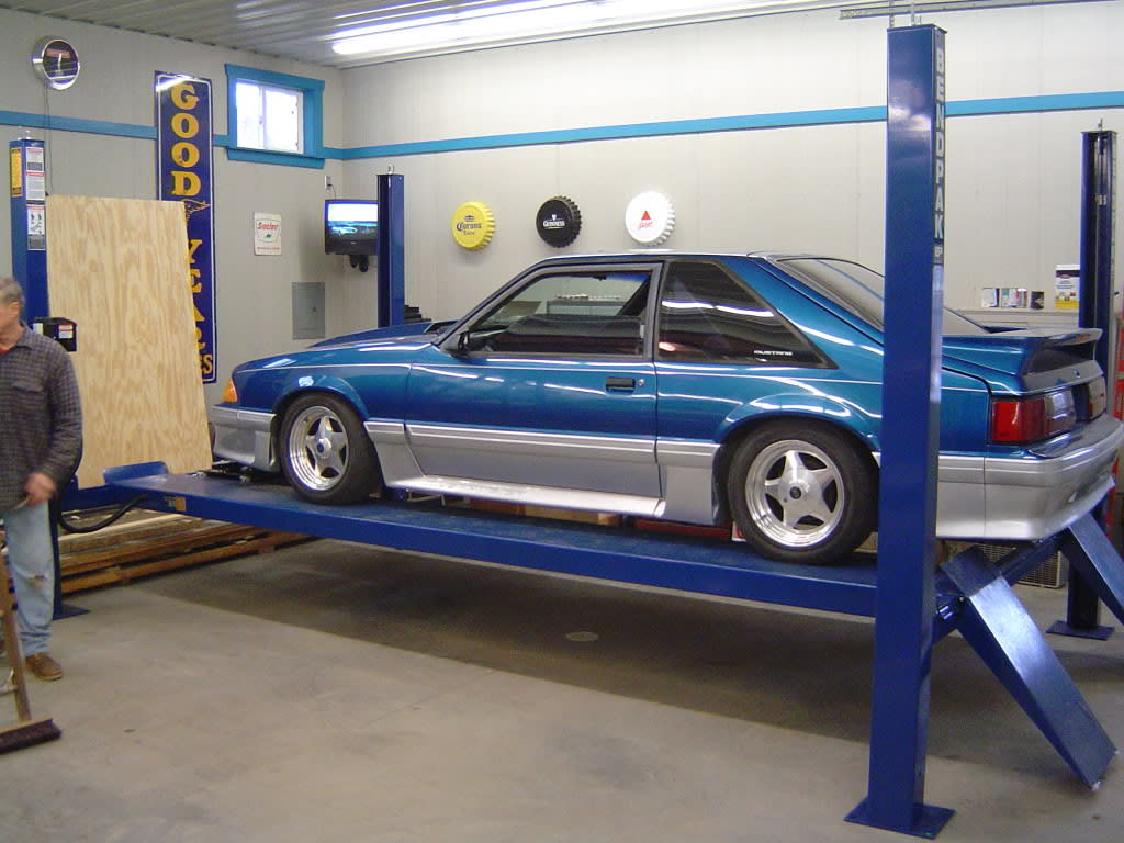 Four Post Car Lift With Vehicle In Professional Garage