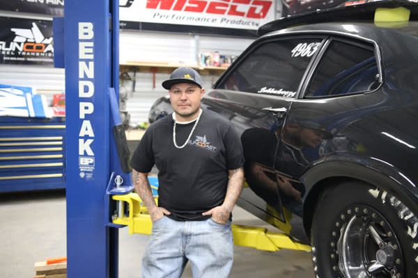 Technician Standing By BendPak Two Post Lift In Shop