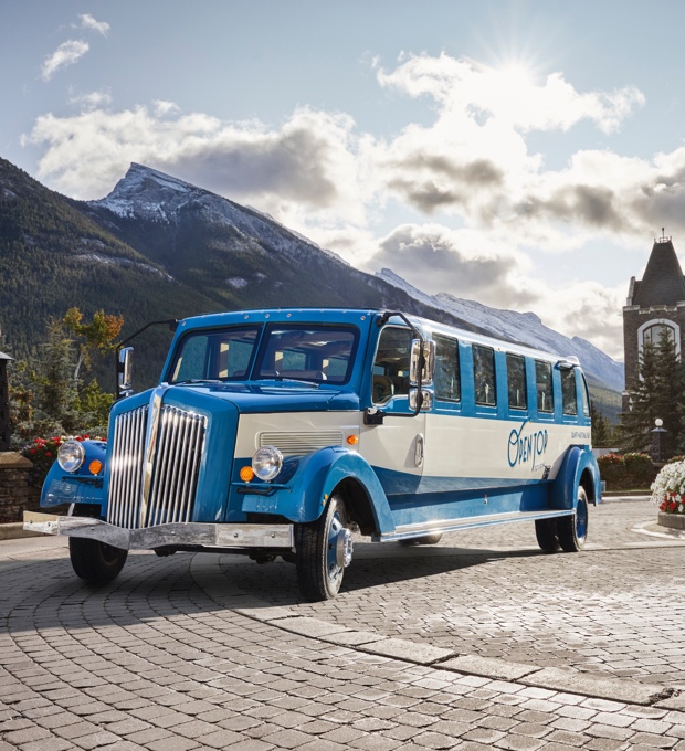 One of Pursuit's vintage-inspired open-top touring vehicles is seen against a mountain backdrop. 