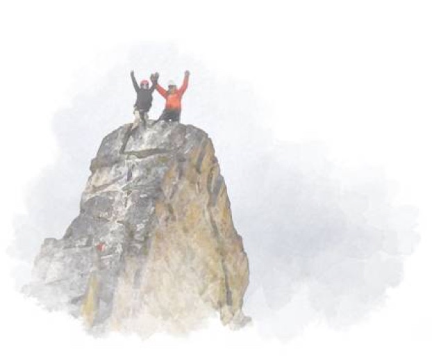 Two hikers celebrate after summiting a mountain peak.