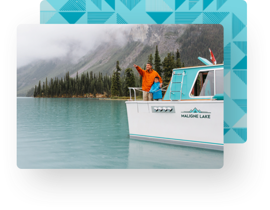 A father and son enjoy the scenery from the stern of a Maligne Lake tour boat that features our branding work on its hull.