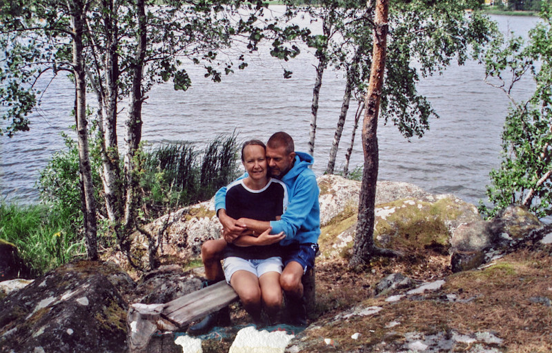 Ungt par håller om varandra på en bänk vid en sjö