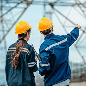 Utility workers in safety gear inspecting electrical power lines.