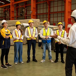 Industrial team in safety gear discussing work inside a warehouse.