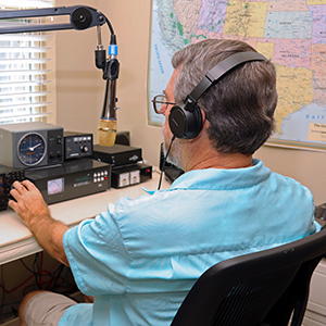 Radio operator using ham radio equipment with headphones.