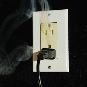 Electrical outlet smoking around a plugged-in power cord.