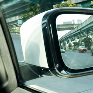 A car’s side-view mirror reflects approaching vehicles on a multilane road.