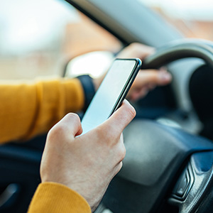 A man texting on his phone while driving his car.