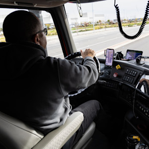 In-cab view of a male trucker driving on the highway.