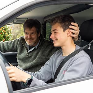 A driving instructor sits beside a young driver and provides guidance while the student practices driving a car.