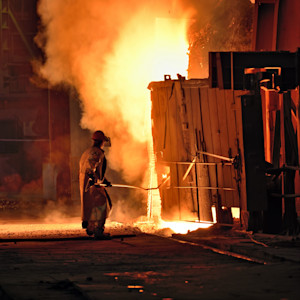 A worker in a steel making factory attempts to put out an explosion caused by combustible dust.