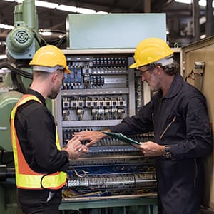 Industrial technicians inspecting an electrical control cabinet.