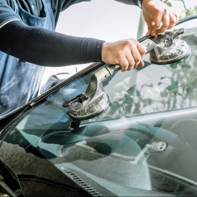 A mechanic removing and replacing a car windshield.