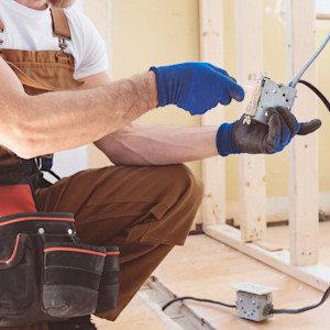 A Caucasian male electrician tests a GFCI outlet during a house rewire.
