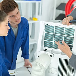 Technicians inspecting and cleaning an industrial air conditioning unit.