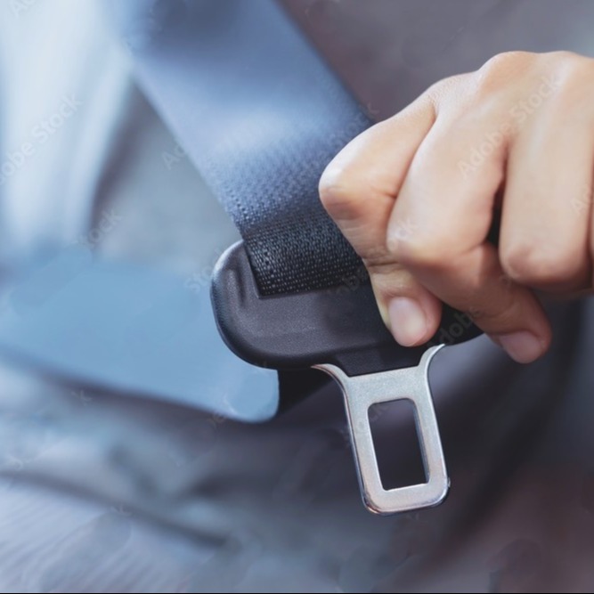 A hand buckling a seat belt in a car.
