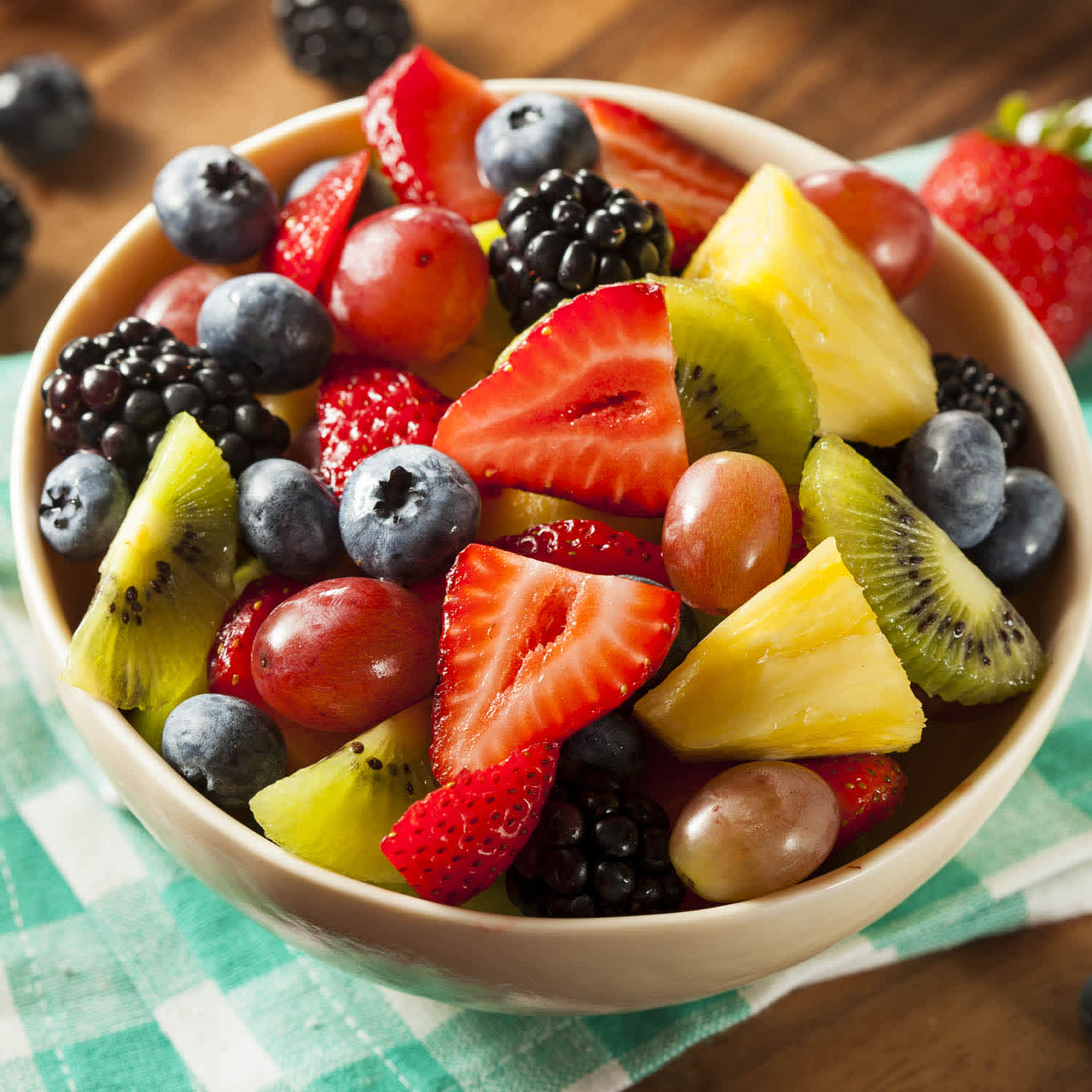 Salada de frutas em um pote sobre mesa com toalha xadrez