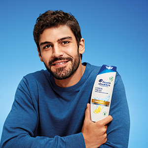Mann präsentiert eine Flasche Head & Shoulders Citrus Fresh Shampoo und lächelt.