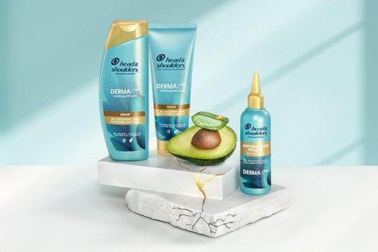 Head & Shoulders Dermaxpro Repair Shampoo, Pflegespülung und Kopfhautmaske neben Avocado- und Aloestückchen.