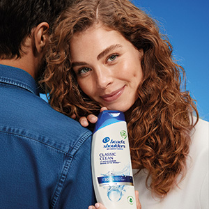 Frau hält eine Flasche Head & Shoulders Classic Clean Shampoo und lehnt sich an einen Mann.