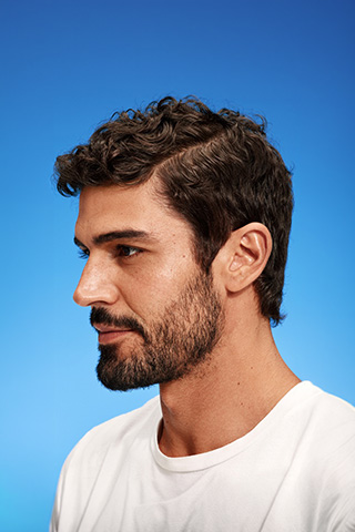 Ein Mann mit gepflegtem Haar vor blauem Hintergrund.
