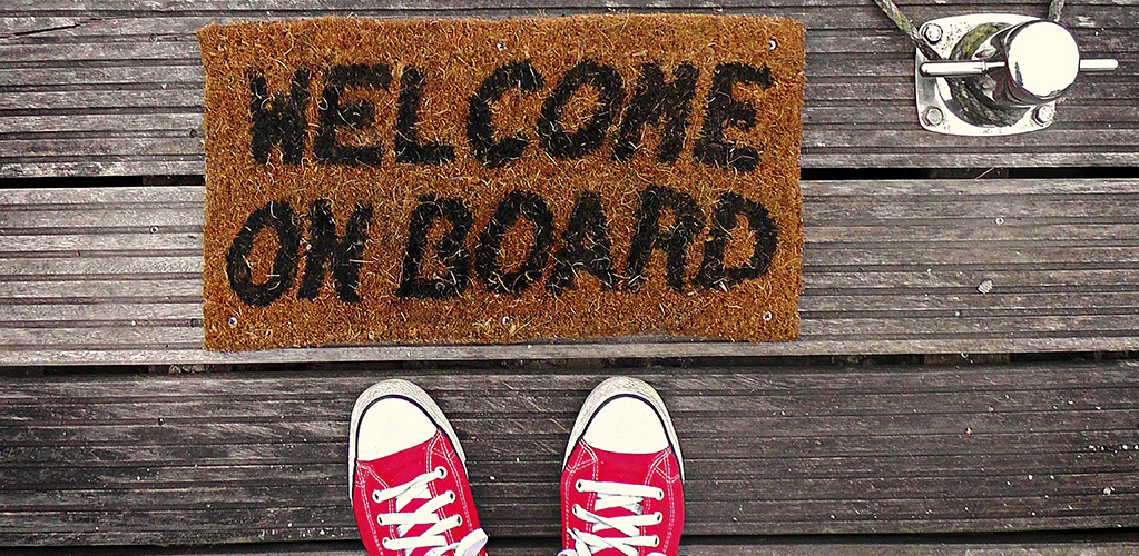 <html><head></head><body><p>A pair of shoes with a mat which says Welcome on board</p></body></html>