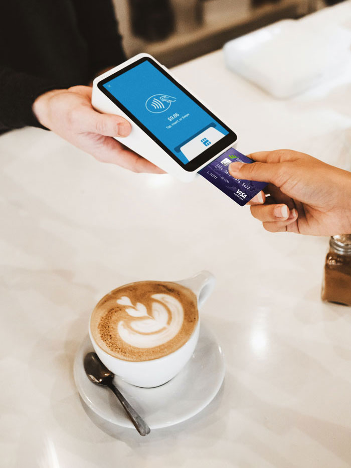 A person paying for coffee using a credit card with a mobile card reader