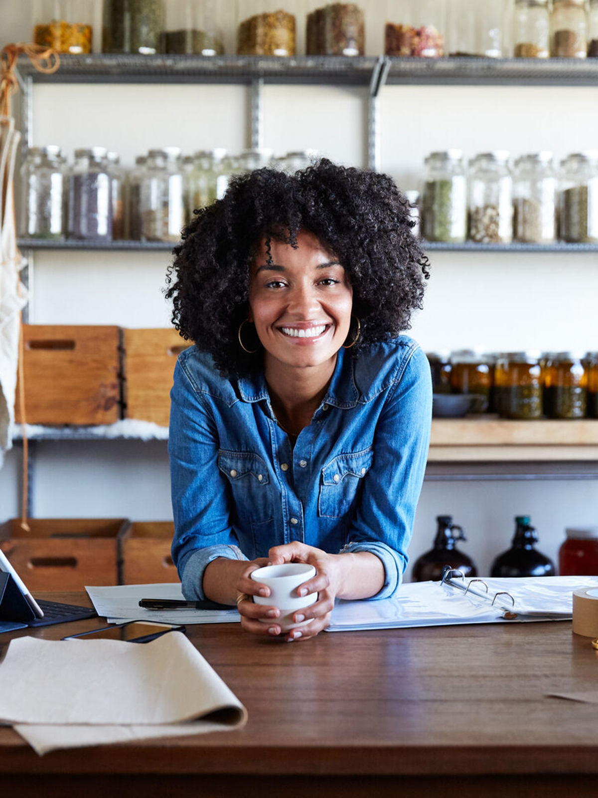Woman leaning on desk and smiling in her skincare studio