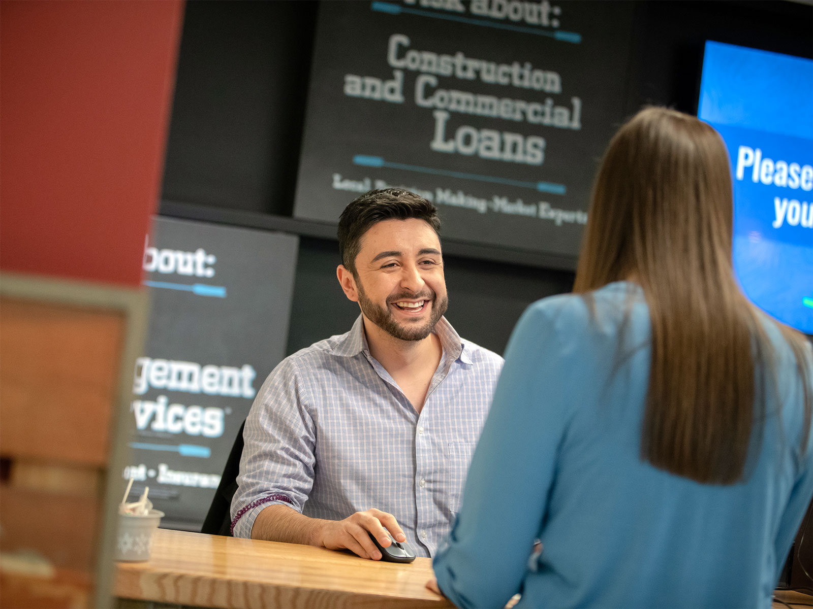 A male Elevations teller greets a customer at an Elevations branch 