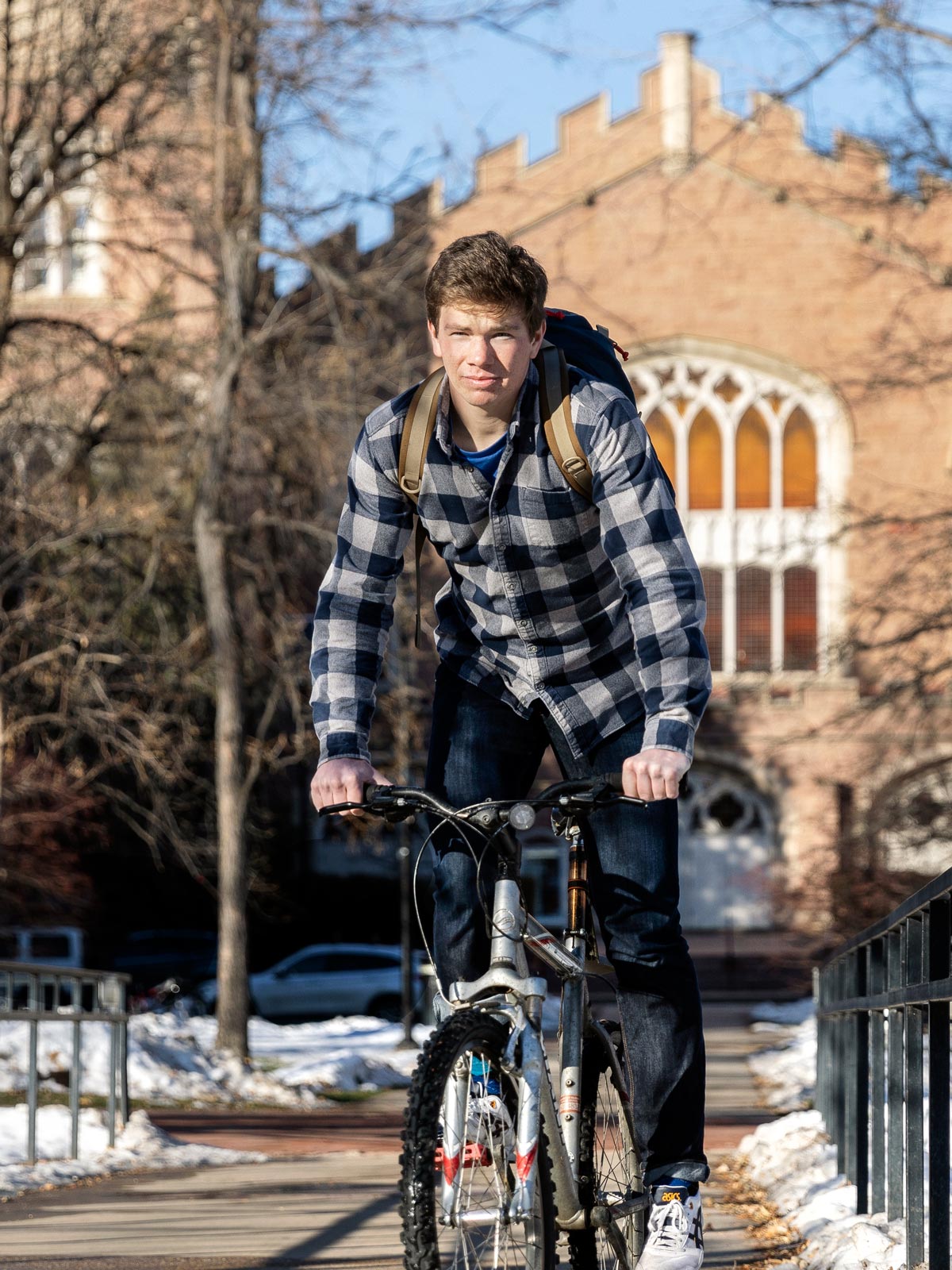 Young man on his bike riding in front of Macky Auditorium at the University of Colorado