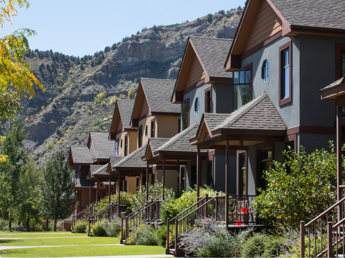 Hilera de casas con patios verdes que dan a las colinas o montañas